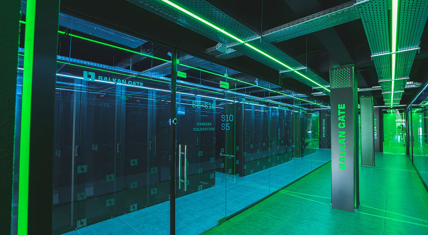Green-lit server corridor inside Balkan Gate Thessaloniki Data Center showcasing racks and cooling systems.